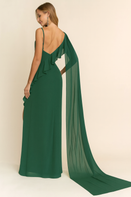 Un vestido elegante en color verde esmeralda, de corte largo y fluido, que destaca por su escote original con drapeado, un detalle de capa en la espalda y una abertura lateral con volantes, aportando un estilo refinado y glamuroso ideal para eventos formales.